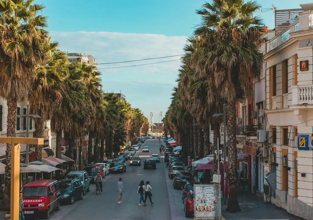 People walking a sunlit Tirana street