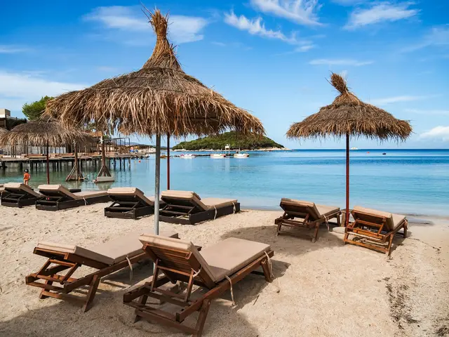 Sandy Ksamil beach with straw umbrellas